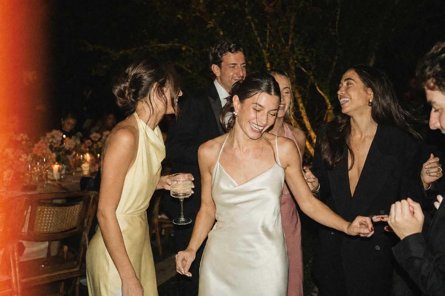 Friends caught mid-laugh on a wedding dance floor.